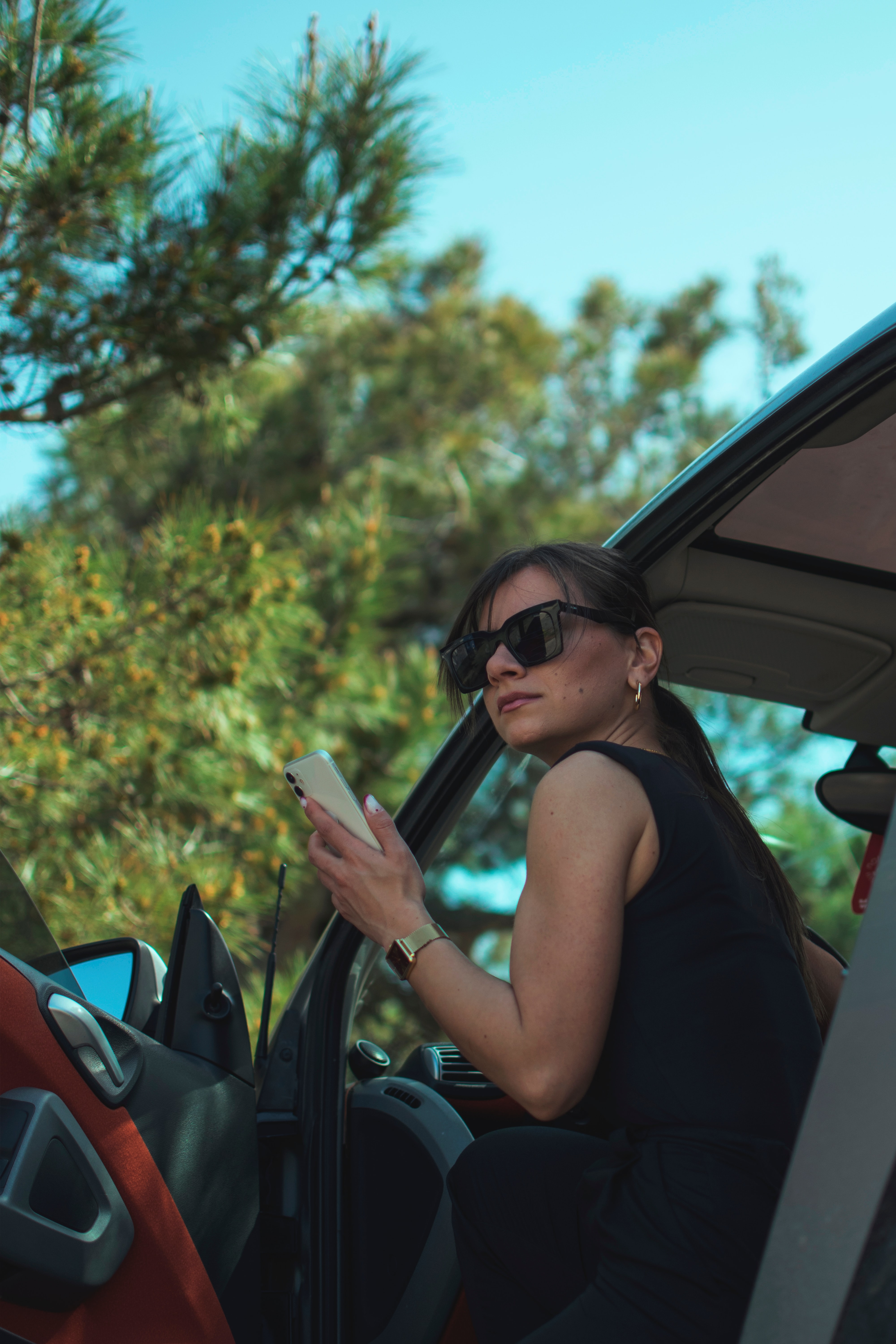 woman in black tank top wearing black sunglasses holding smartphone