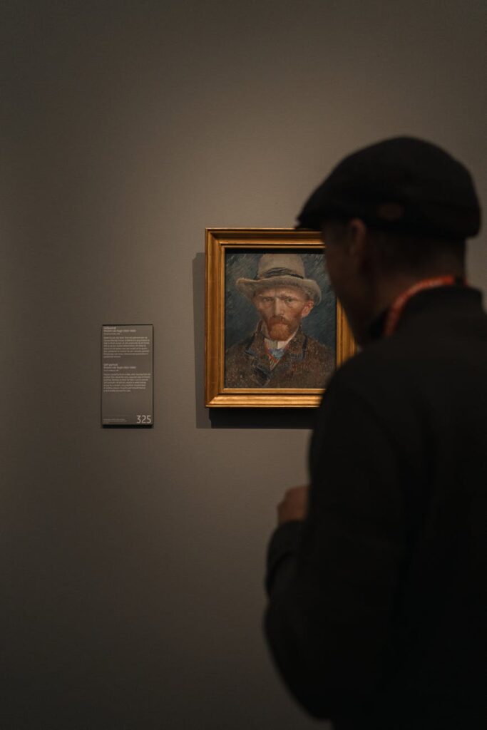 man standing by van gogh painting in rijksmuseum in amsterdam